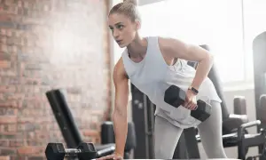 Kvinna tränar med hantlar på gym, fokuserad på att gå ner i vikt.
