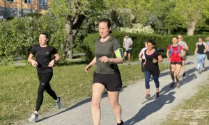 En grupp löpare, mestadels kvinnor, tar sig fram på en grusväg i en park. De är på väg att springa en mil i det vackra vårvädret.