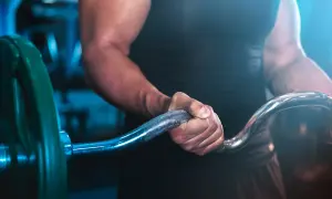 En person med starka armar håller i en skivstång, redo för ett intensivt crossfit pass.