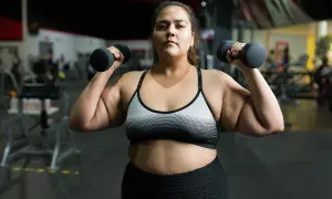 En kvinna lyfter hantlar på gymmet, en del av hennes träningsresa för att gå ner i vikt.