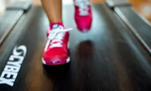 Fötter i rosa löparskor på ett löpband med texten "CYBEX". Kanske är det 12, 3, 30 svenska som tränar?