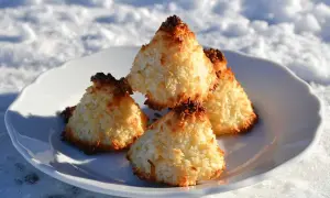 Nyttiga kokostoppar på en vit tallrik i snön. Perfekt fika för kalla dagar.