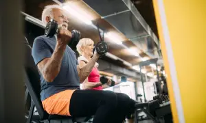 Äldre par tränar med hantlar på gym. De visar att sarkopeni betyder minskad muskelmassa, men att träning kan motverka detta.