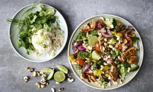 Två tallrikar med nyttig grillmat: ris med koriander och grönsaker, samt en wok med kyckling, broccoli, paprika, cashewnötter och lime.