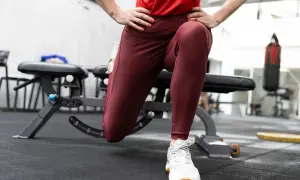 En person utför en split squat i ett gym. En boxningssäck syns i bakgrunden.