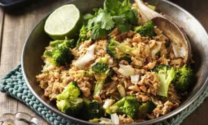 En skål med stekt ris med broccoli, jordnötter och en limeklyfta. En perfekt nyttig lunch.