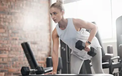 Kvinna tränar med hantlar på gym, fokuserad på att gå ner i vikt.