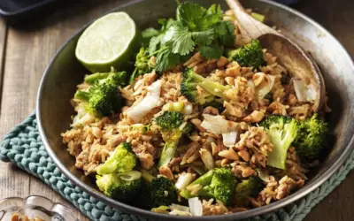 En skål med stekt ris med broccoli, jordnötter och en limeklyfta. En perfekt nyttig lunch.