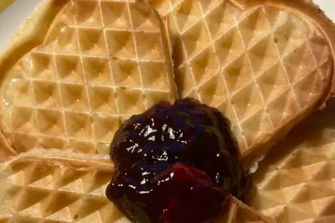 Hjärtformade veganska våfflor med en klick mörkt sylt. Perfekt för en mysig fika.