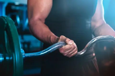 En person med starka armar håller i en skivstång, redo för ett intensivt crossfit pass.