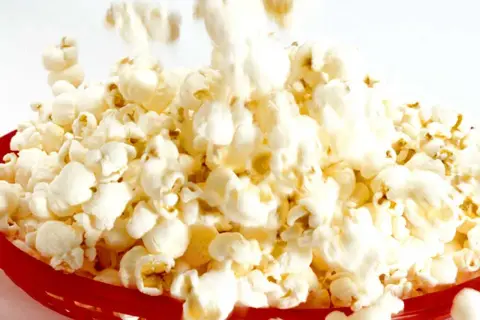 En röd korg fylld med fluffiga, luftpoppade popcorn. En härlig syn för alla popcornälskare!