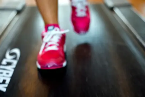 Fötter i rosa löparskor på ett löpband med texten "CYBEX". Kanske är det 12, 3, 30 svenska som tränar?
