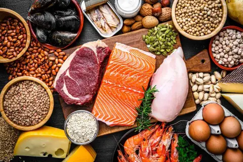En variation av proteinrika livsmedel: biff, lax, kyckling, räkor, musslor, bönor, linser, nötter, frön, ägg och ost. Perfekt för att optimera ditt protein per kg.