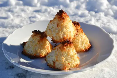 Nyttiga kokostoppar på en vit tallrik i snön. Perfekt fika för kalla dagar.