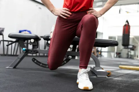 En person utför en split squat i ett gym. En boxningssäck syns i bakgrunden.
