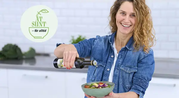 Glad kvinna häller olivolja över en fräsch sallad. En logotyp med texten "ÄT SUND - för alltid" syns i bakgrunden, vilket antyder en livsstil med fet mat och hälsosamma val.