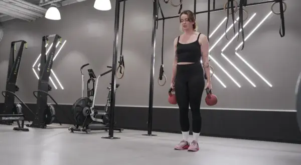 Tjej med kettlebells i gym, redo för sitt träningsschema.