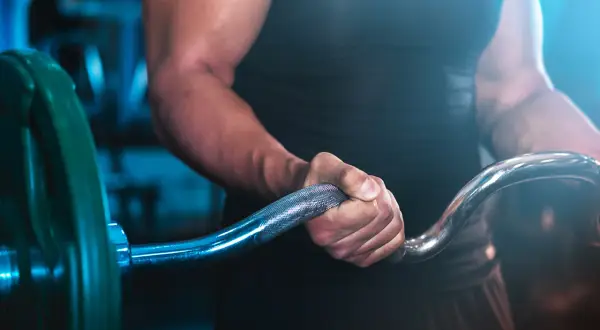 En person med starka armar håller i en skivstång, redo för ett intensivt crossfit pass.