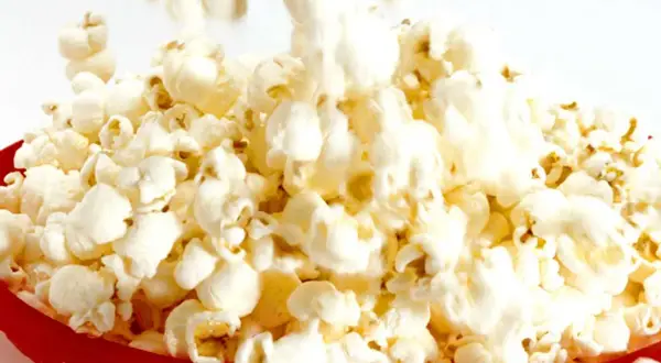 En röd korg fylld med fluffiga, luftpoppade popcorn. En härlig syn för alla popcornälskare!