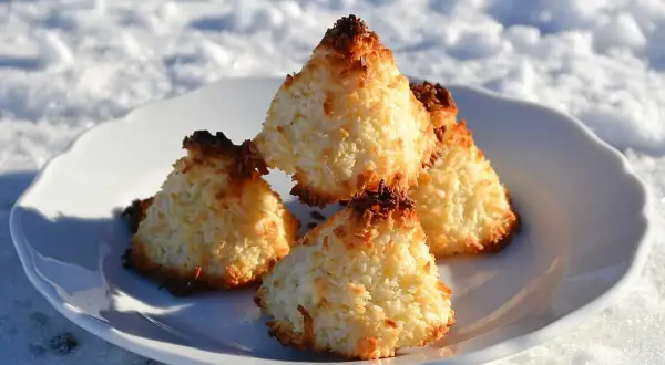 Nyttiga kokostoppar på en vit tallrik i snön. Perfekt fika för kalla dagar.
