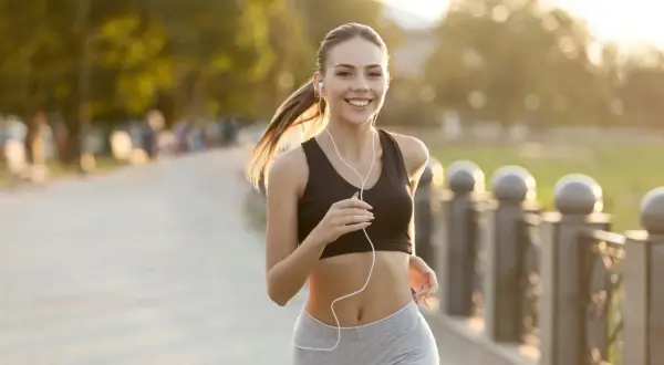 Glad kvinna springer i solnedgången, sista veckan innan halvmarathon.