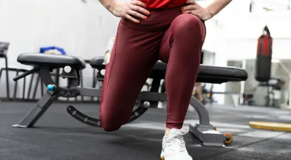 En person utför en split squat i ett gym. En boxningssäck syns i bakgrunden.
