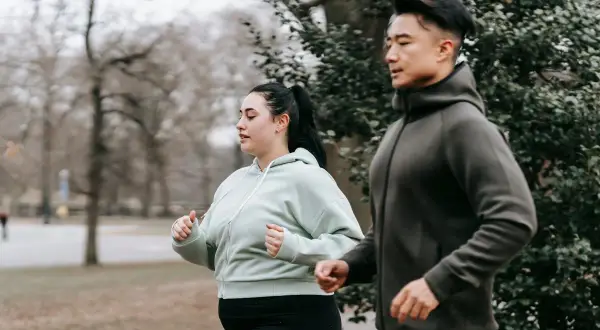 Ett par joggar utomhus, en del av deras resa för att gå ner i vikt utan att banta.