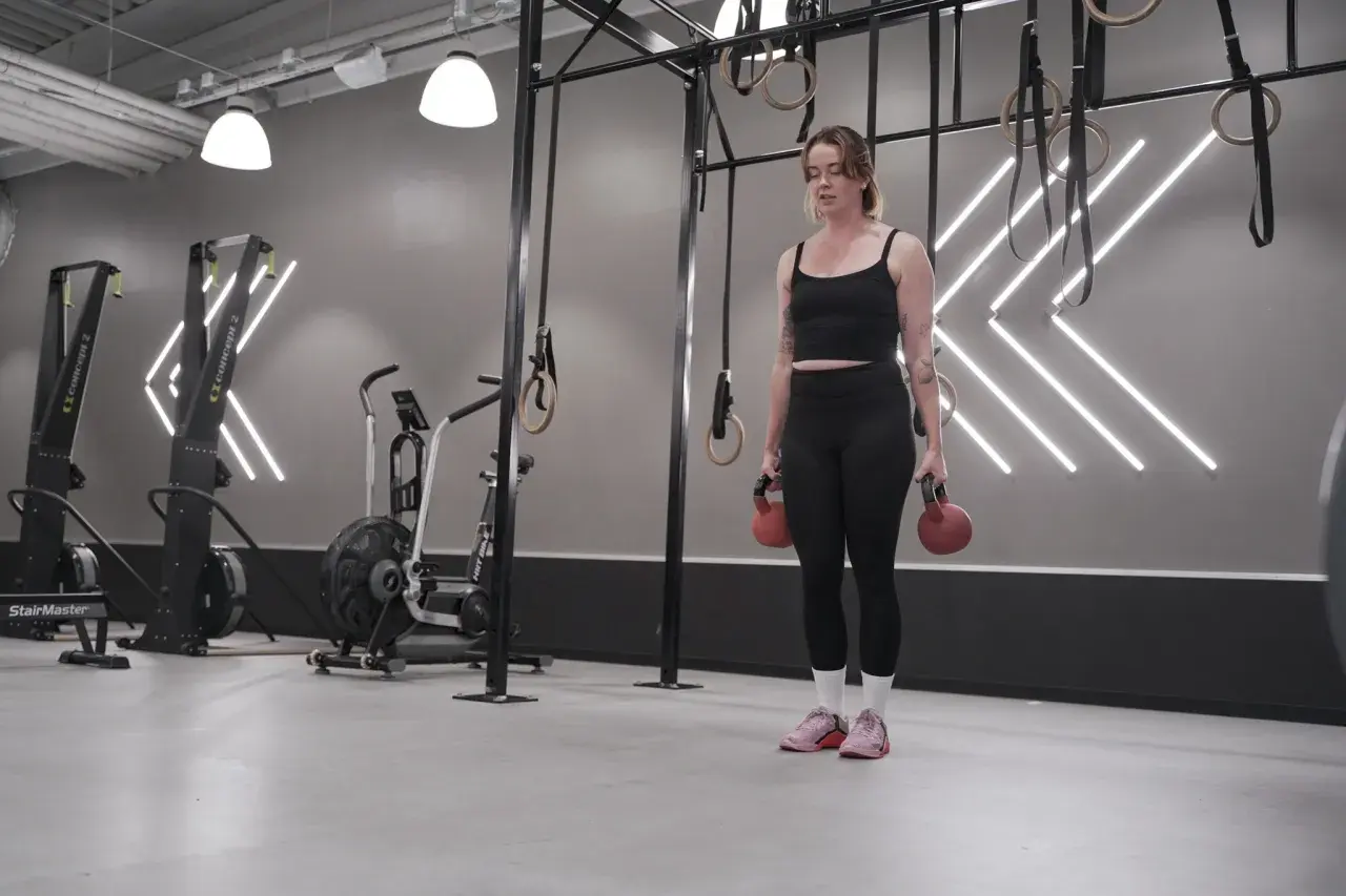 Tjej med kettlebells i gym, redo för sitt träningsschema.