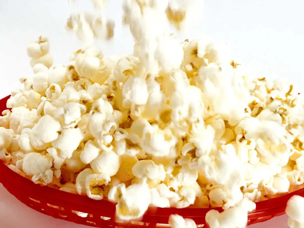 En röd korg fylld med fluffiga, luftpoppade popcorn. En härlig syn för alla popcornälskare!