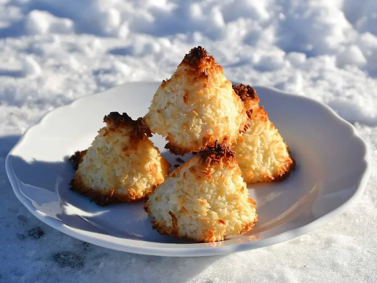 Nyttiga kokostoppar på en vit tallrik i snön. Perfekt fika för kalla dagar.