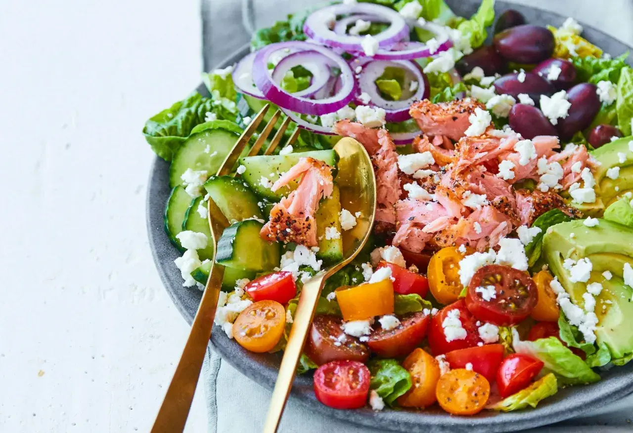 En fräsch sallad med lax, avokado, tomat, gurka, rödlök och fetaost. Ett perfekt medelhavskost recept för en lätt lunch.