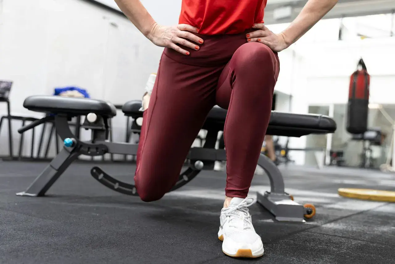 En person utför en split squat i ett gym. En boxningssäck syns i bakgrunden.