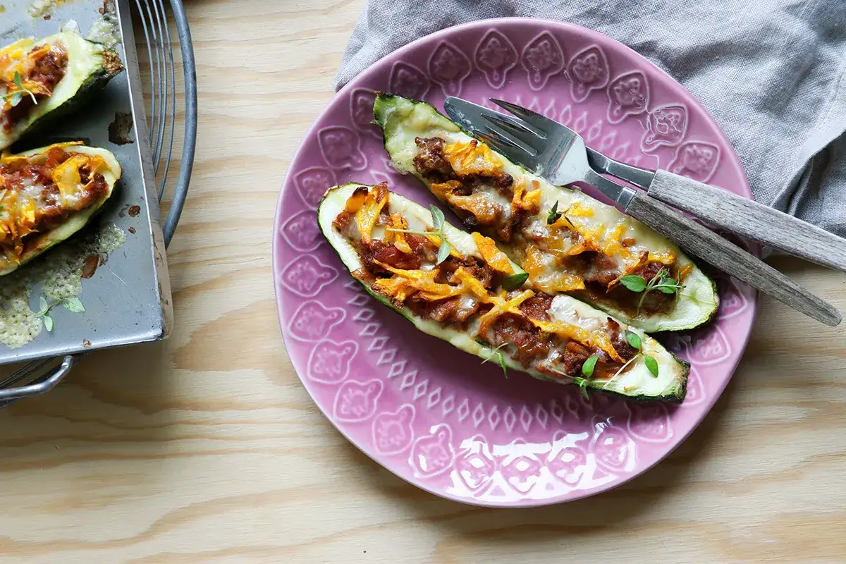 Två halverade zucchini fyllda med köttfärs och ost, redo att avnjutas som en del av nyttiga recept.