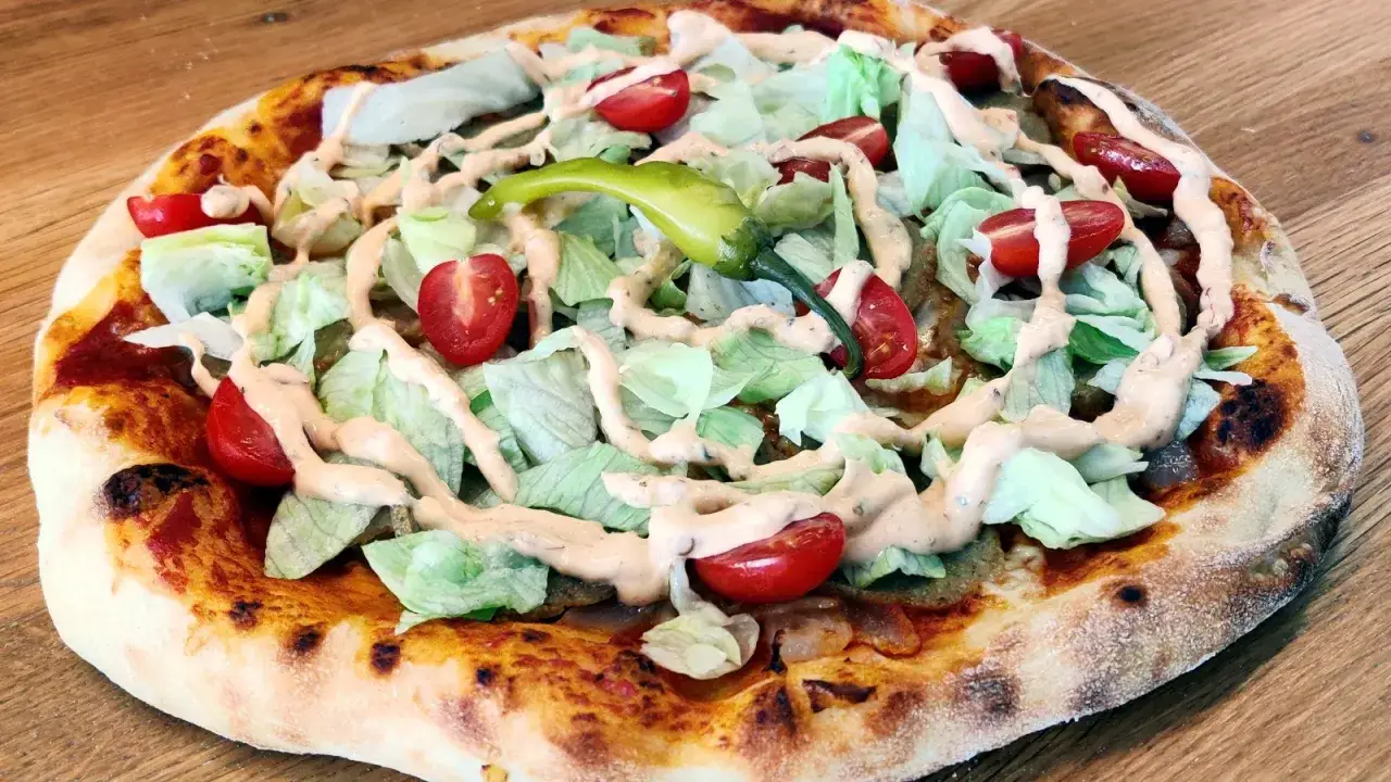 En kebabpizza med sallad, tomater och dressing. En läcker rätt, men tänk på kebabpizza kalorier!
