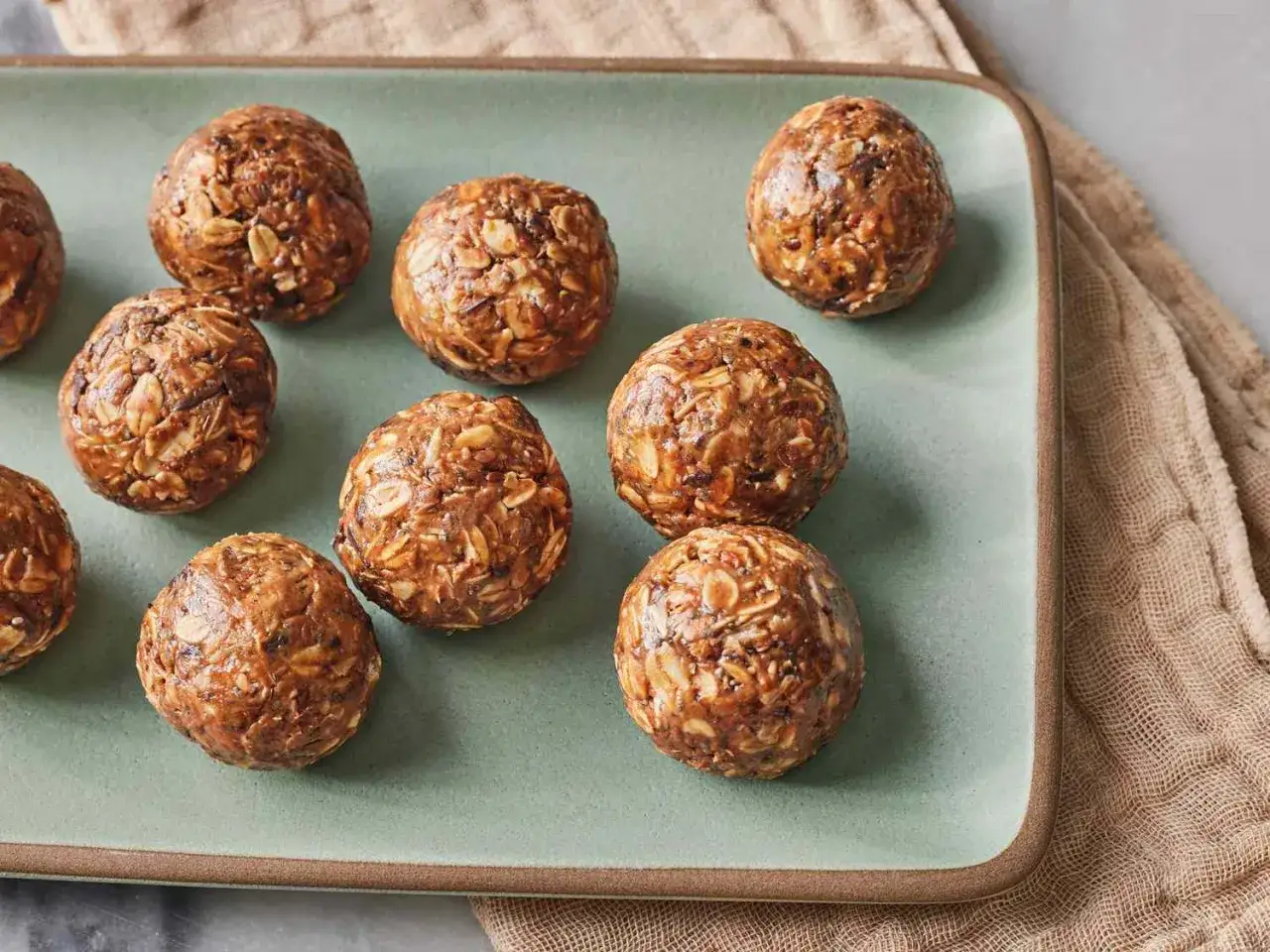 Flera protein chokladbollar ligger på en ljusgrön bricka. De ser goda och energigivande ut.