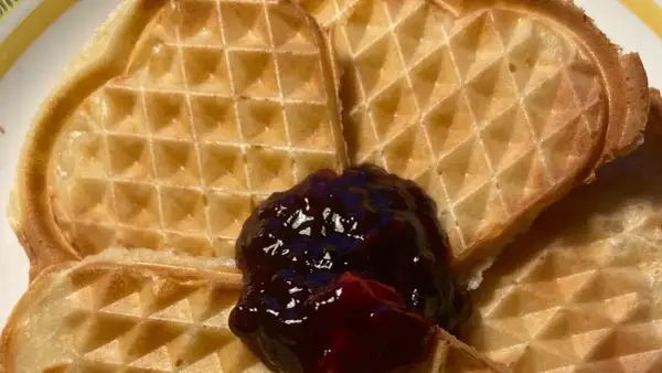Hjärtformade veganska våfflor med en klick mörkt sylt. Perfekt för en mysig fika.