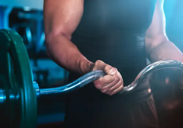En person med starka armar håller i en skivstång, redo för ett intensivt crossfit pass.
