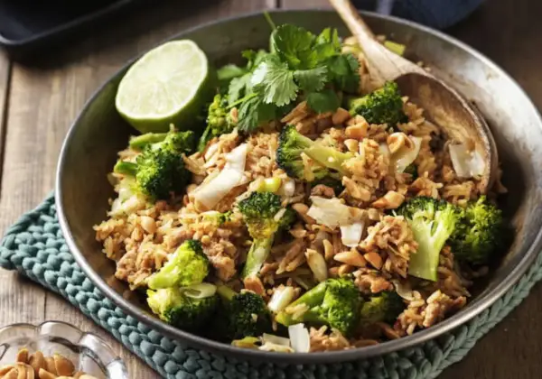 En skål med stekt ris med broccoli, jordnötter och en limeklyfta. En perfekt nyttig lunch.