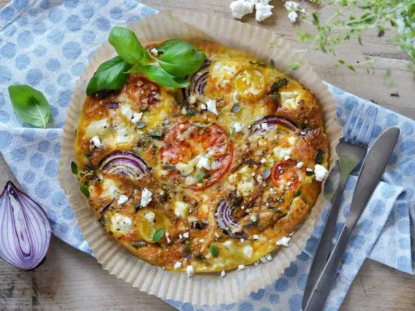 En gyllene omelett i airfryer med tomat, rödlök och fetaost, toppad med färsk basilika. Perfekt för en snabb och smakrik måltid.